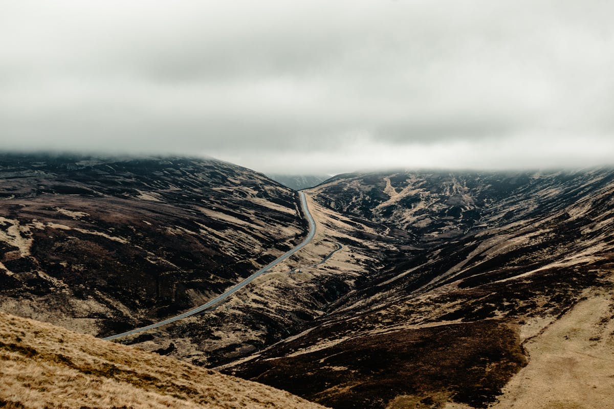 Scenic Scottish Highlands with moody skies and winding road