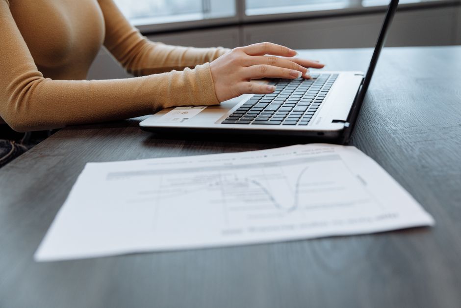 Close-up of hands typing on a laptop keyboard while completing an online application