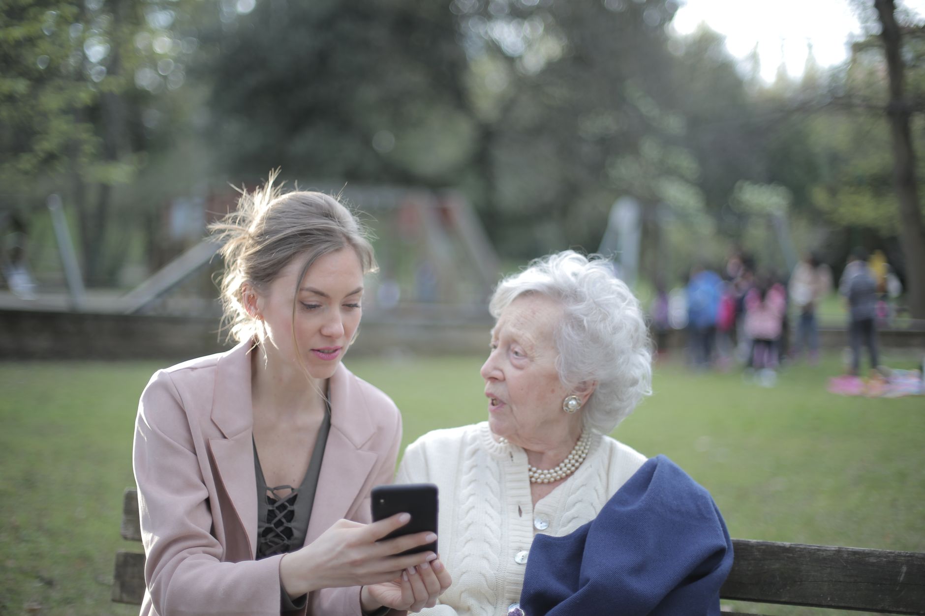 Younger adult helping an elderly relative fill in a form on a smartphone
